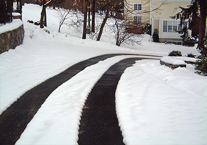 Asphalt driveway with heated tire tracks.